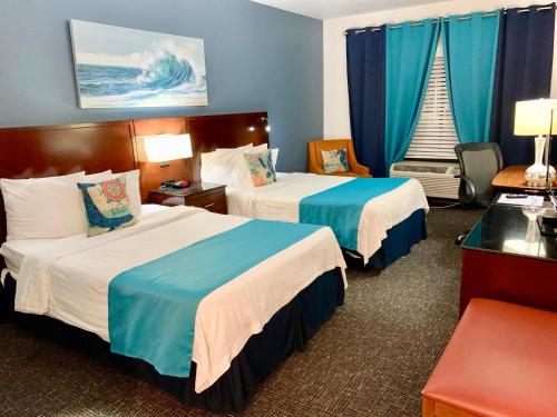 彭萨科拉Hotel Pensacola的两张位于酒店客房的床,配有蓝色窗帘