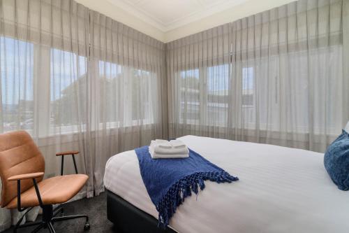 罗托鲁瓦Lakes Lodge Rotorua的一间卧室配有一张床、一把椅子和窗户。