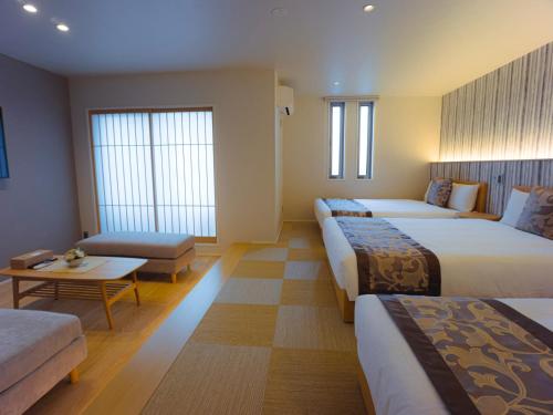 福冈GRAND BASE Hakata Sumiyoshi的酒店客房,设有三张床和一张沙发