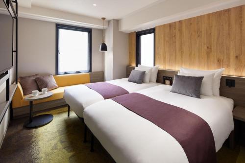 东京the b ochanomizu的酒店客房,设有两张床和一张沙发