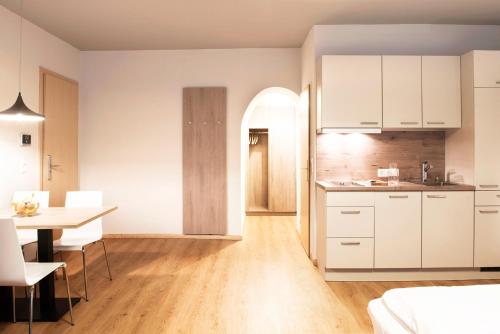 因斯布鲁克Daxburg Apartments的厨房以及带白色橱柜和桌子的用餐室。