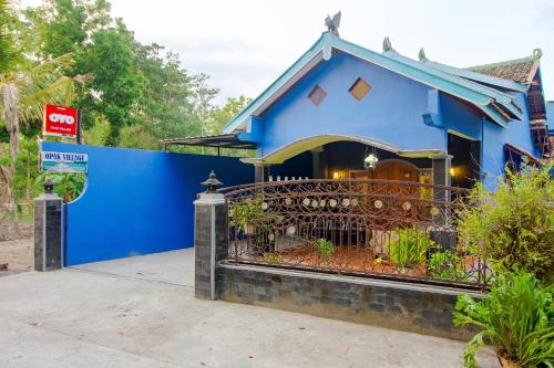 班图尔OYO 2047 Opak Village Bed & Breakfast的前面有栅栏的蓝色房子