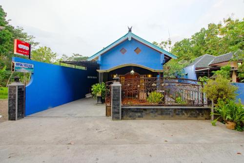 班图尔OYO 2047 Opak Village Bed & Breakfast的一座带门和大楼的蓝色房子