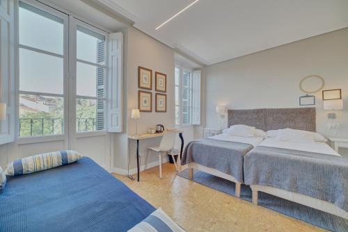 潘普洛纳Pensión Mendi的一间卧室设有两张床、一张桌子和窗户。