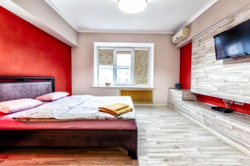 阿拉木图420 Апартаменты в центре возле Арбата Отлично подходят для командированных и туристов的卧室设有红色的墙壁、一张床和一台平面电视