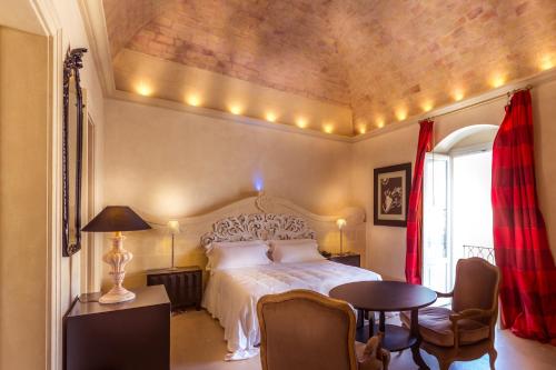 马泰拉帕拉索加堤尼豪华酒店的卧室配有一张床和一张桌子及椅子