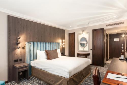 伦敦伦敦法院酒店的一间卧室配有一张大床和蓝色床头板