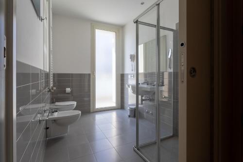 里米尼格米酒店的一间带卫生间、水槽和镜子的浴室