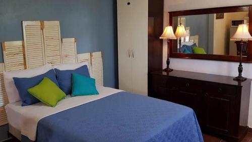 棕榈滩Sandcastle Beach Apartments的一间卧室配有一张带蓝色和绿色枕头的床
