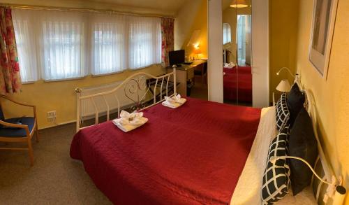格奥尔根塔尔Amadeus Boutique Hotel Deutscher Hof的一间卧室配有红色的床和2条毛巾