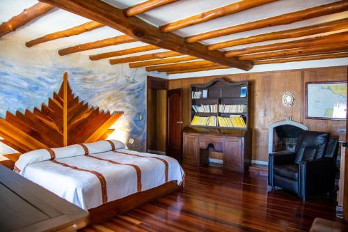 圣卡塔里纳帕洛波特赞珀克度假酒店的一间卧室配有一张床、一把椅子和一个壁炉