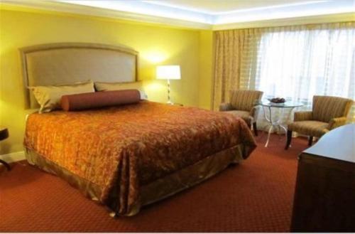 拉斯维加斯赛马会度假公寓的一间卧室配有一张大床和一张桌子及椅子
