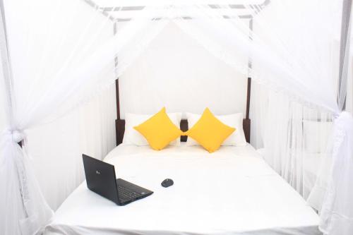 锡吉里亚Hotel BEJEWELLED Sigiriya的一间卧室,床上配有笔记本电脑和窗帘
