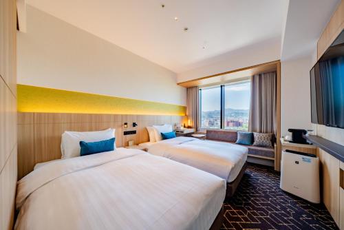 札幌Keio Prelia Hotel Sapporo的配有大窗户的酒店客房内的两张床