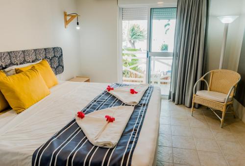 塔曼达雷Baía Branca Beach Resort的一间卧室,床上有红色的鲜花