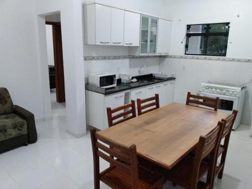 帕罗卡Apartamentos Praia do Sonho的厨房以及带木桌和椅子的用餐室。