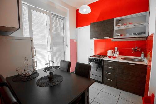 奥西耶克FLAMINGOS Apartman & Fitness OSIJEK - blizina Bolnice KBC Osijek的厨房拥有红色的墙壁,配有桌椅