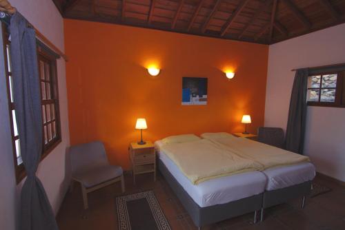 TodoqueCasa Tanausu的一间卧室设有橙色墙壁、一张床和一把椅子