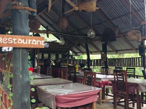 锡吉里亚Tree house Hostel Sigiriya的一间带桌椅和屋顶的餐厅