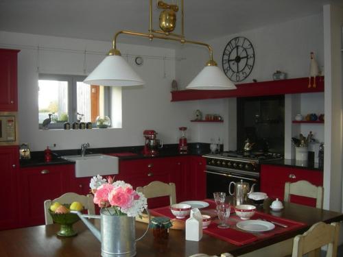Baulon本哈特乐住宿加早餐旅馆的厨房配有红色橱柜和鲜花桌