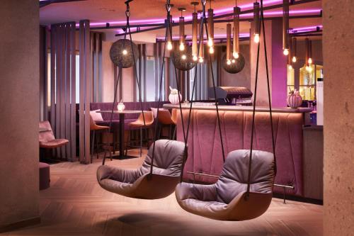 图克斯Adler Inn Tyrol Mountain Resort SUPERIOR的一间带椅子的餐厅和一间拥有紫色照明的酒吧