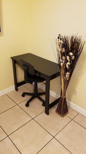 奥兰多B Private Bedroom的一张带椅子和花瓶的黑色书桌