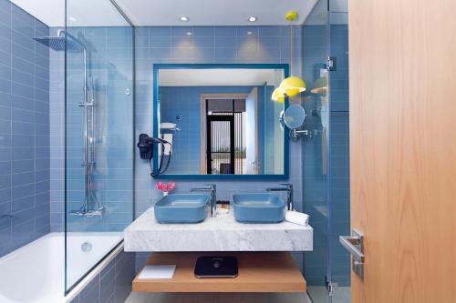 迪拜C Central Hotel and Resort The Palm的蓝色的浴室设有水槽和镜子