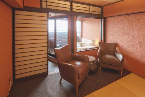 伊豆阿如栖旅馆的一间设有两把椅子和窗户的等候室