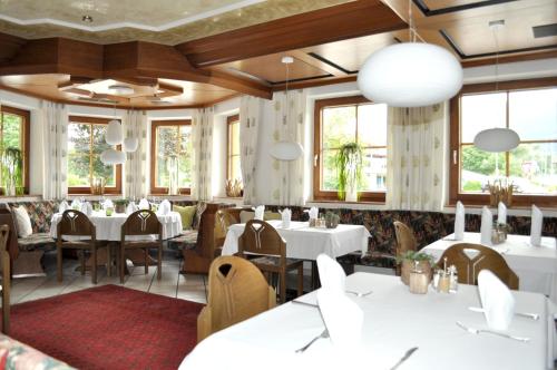 Breitenbach am Inn肖伯尔宾馆的餐厅设有白色的桌椅和窗户。