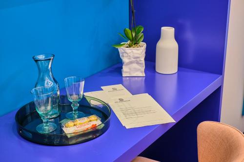 布加勒斯特Vilacrosse Boutique Inn的蓝桌,带玻璃杯和一瓶的托盘