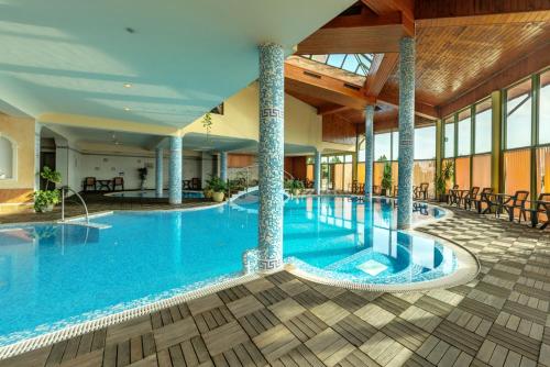 韦林格勒SPA Hotel Olymp的酒店的大型游泳池配有桌椅