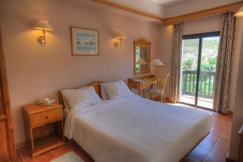 克伦蒂圣帕特里克酒店的一间卧室配有一张床、一张书桌和一个窗户。