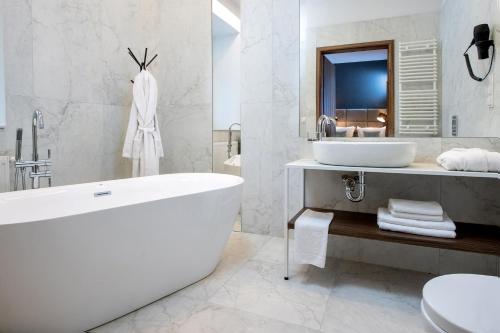 克拉科夫Hotel M29的白色的浴室设有浴缸和水槽。