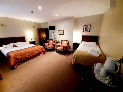 基尔肯尼JBs Bar & Guest Accommodation的酒店客房,配有两张床和椅子