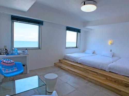 横须贺市Mykonos Resort Miura / Vacation STAY 62208的一间卧室配有两张床、一张桌子和两个窗户。