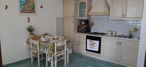 波西塔诺安提卡马希纳别墅的厨房配有白色橱柜和桌椅