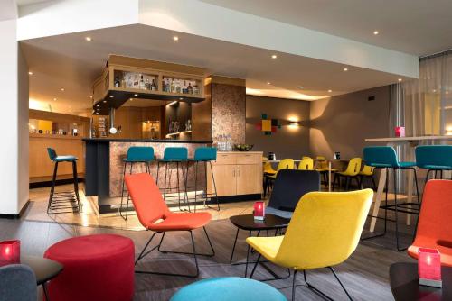 汉诺威Ramada by Wyndham Hannover的一间设有五颜六色椅子的餐厅和一间酒吧