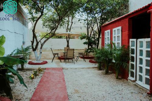 梅里达Casa Lool Beh的一个带桌椅的庭院和一座红色的建筑
