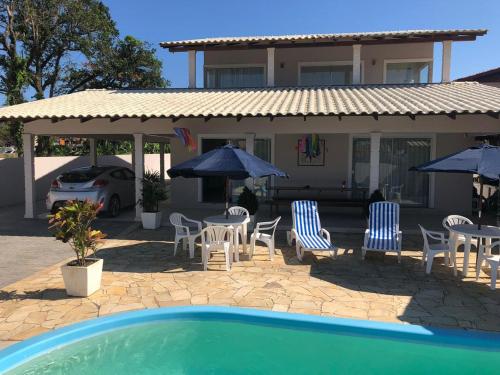 佩尼亚Mundo Livre Guest House的一座带椅子和遮阳伞的房子和一个游泳池