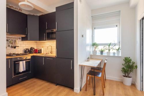 伦敦GuestReady - 1BR Flat Ideally Located In Zone 2 Fits 3的厨房配有黑色橱柜、桌子和窗户。