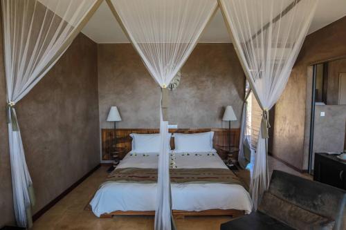 RanohiraIsalo Rock Lodge的一间卧室配有一张带白色床单和窗帘的床