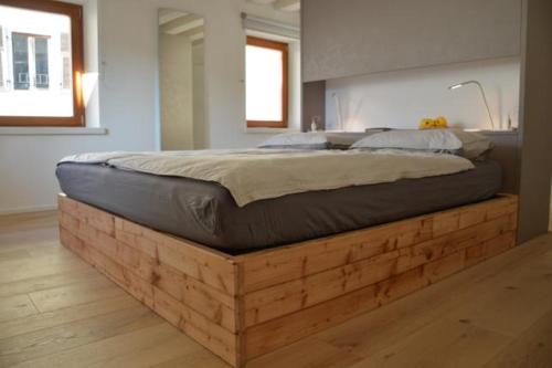 罗韦雷托Dimora Sannicolò - Talento的卧室里一张木平台上的床铺