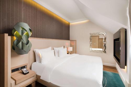 布达佩斯布达佩斯贝克丽笙布鲁酒店的卧室配有一张白色大床和电视。