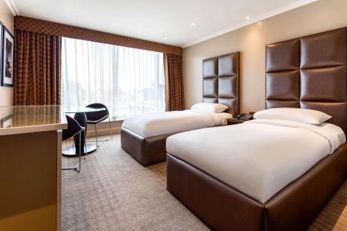 希灵登Radisson Blu Heathrow Hotel, London的酒店客房配有两张床和一张书桌