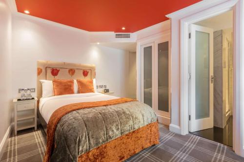 伦敦Radisson Blu Sussex Hotel, London的一间卧室设有一张带橙色天花板的大床