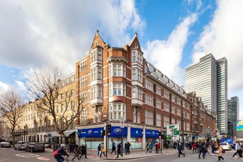 伦敦Radisson Blu Grafton Hotel, London的一群人穿过大楼前的街道