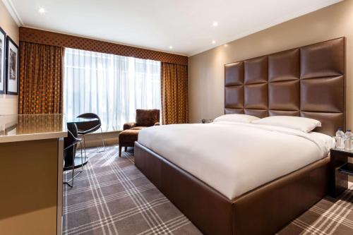 希灵登Radisson Blu Hotel & Conference Centre, London Heathrow的酒店客房设有一张大床和一张书桌。