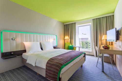 美因河畔法兰克福雷迪森弗兰克福特机场公园旅馆的酒店客房设有一张大床和一张书桌。