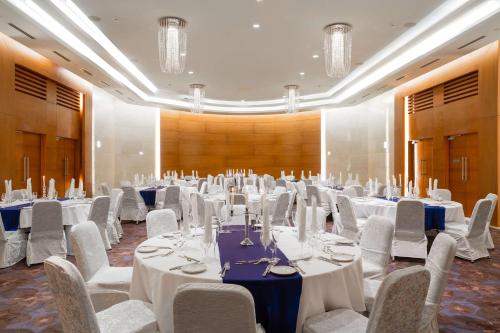 布拉柴维尔布拉柴维尔玛拜波宫丽笙酒店的一个带白色桌椅的大型宴会厅