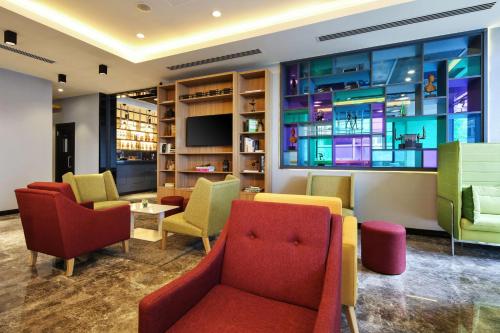 伊兹密尔伊兹密尔丽柏酒店的一间设有五颜六色椅子和电视的等候室